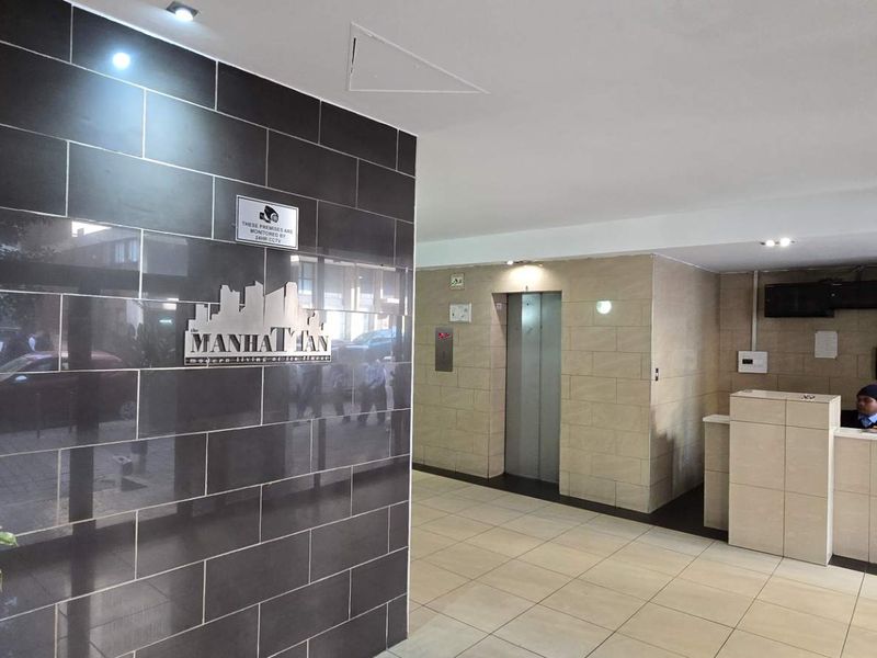 Modern apartment building entrance lobby featuring a reception desk, elevator access, and contemporary tiled finishes.