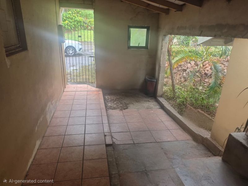 A covered outdoor patio area featuring tiled flooring, exposed timber rafters, and direct access to the garden through a metal security gate.