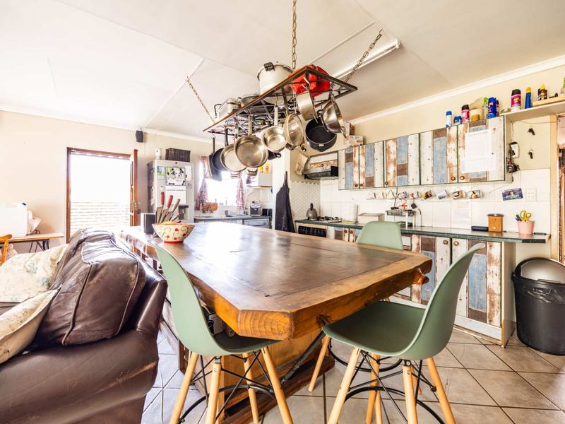 Open plan kitchen and living area featuring tiled flooring, built-in cabinetry, and a central island with a ceiling-mounted pot rack.