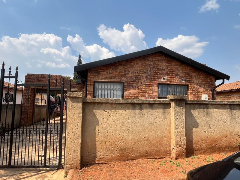 Front view of a face brick house featuring a secure gated entrance and a perimeter boundary wall.