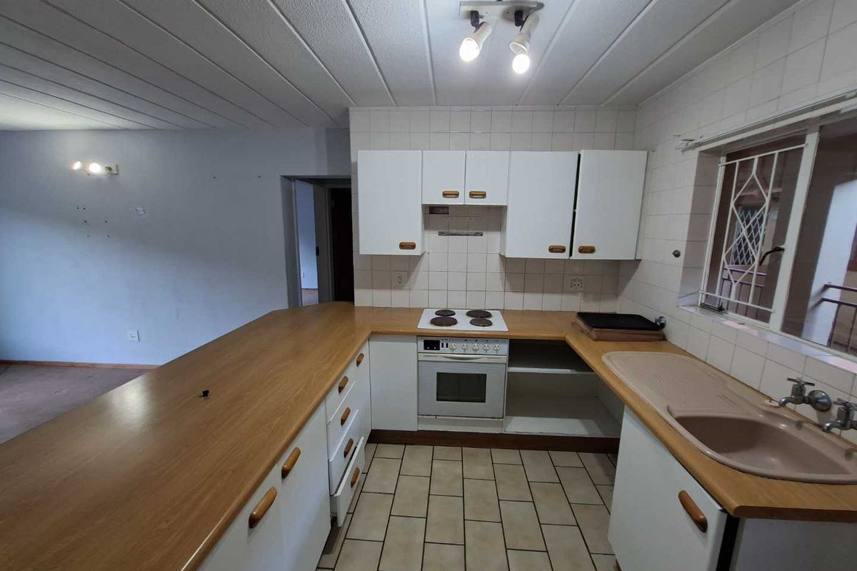 A functional kitchen featuring built-in cabinetry, laminate countertops, an electric stove with oven, and tiled flooring. The space is ready for a modern update.