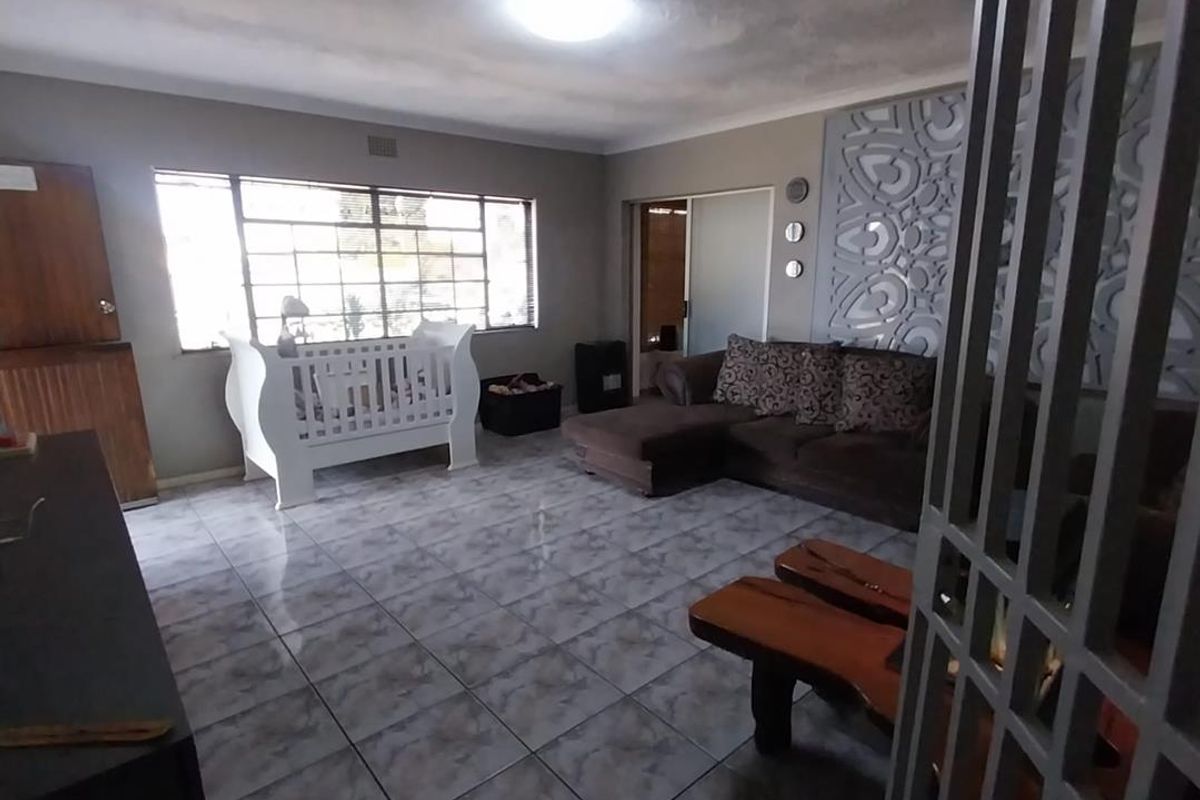Spacious living area featuring tiled flooring, decorative wall paneling, and a secure entrance gate, offering a versatile layout for family living.