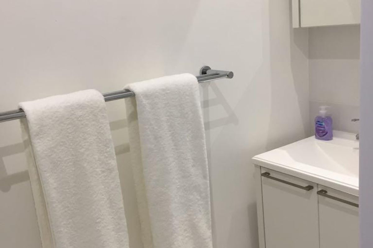 A compact bathroom featuring a wall-mounted vanity with integrated basin, mirrored cabinet, and a chrome towel rail.