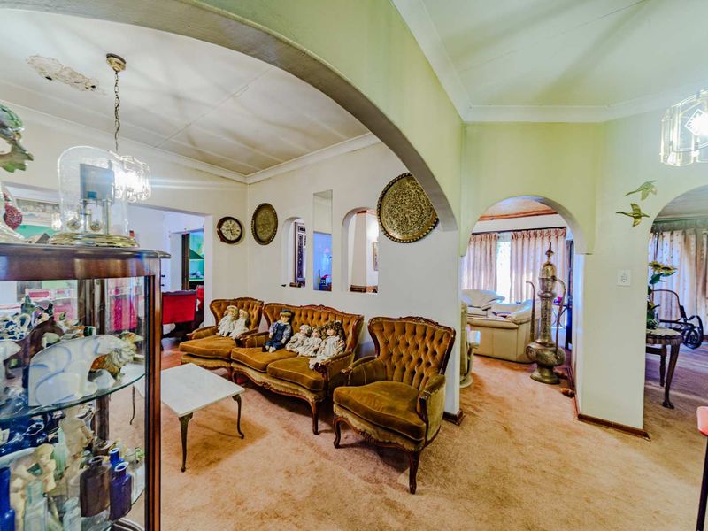 A living area featuring arched architectural transitions, recessed wall niches, and coved ceilings, requiring updates to flooring and ceiling finishes.