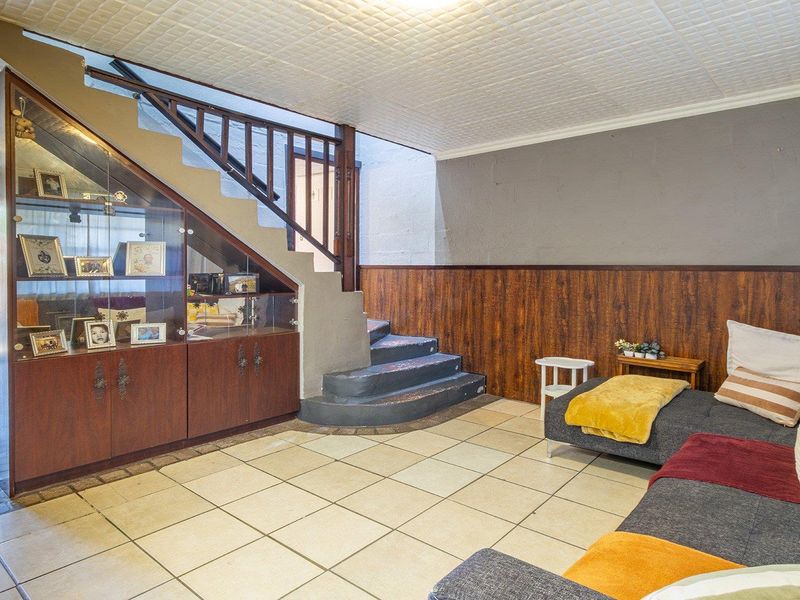 Open plan living area featuring a staircase with built-in under-stair storage, tiled flooring, and wood-paneled walls in a townhouse setting.