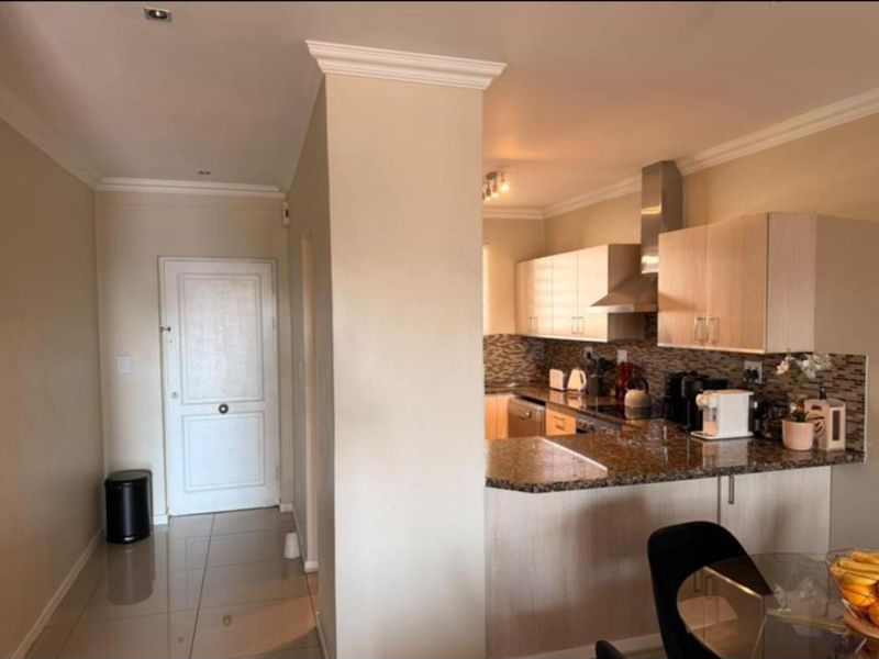 Open plan kitchen featuring granite countertops, mosaic backsplash, and stainless steel extractor fan, seamlessly connected to the entrance area with tiled flooring.