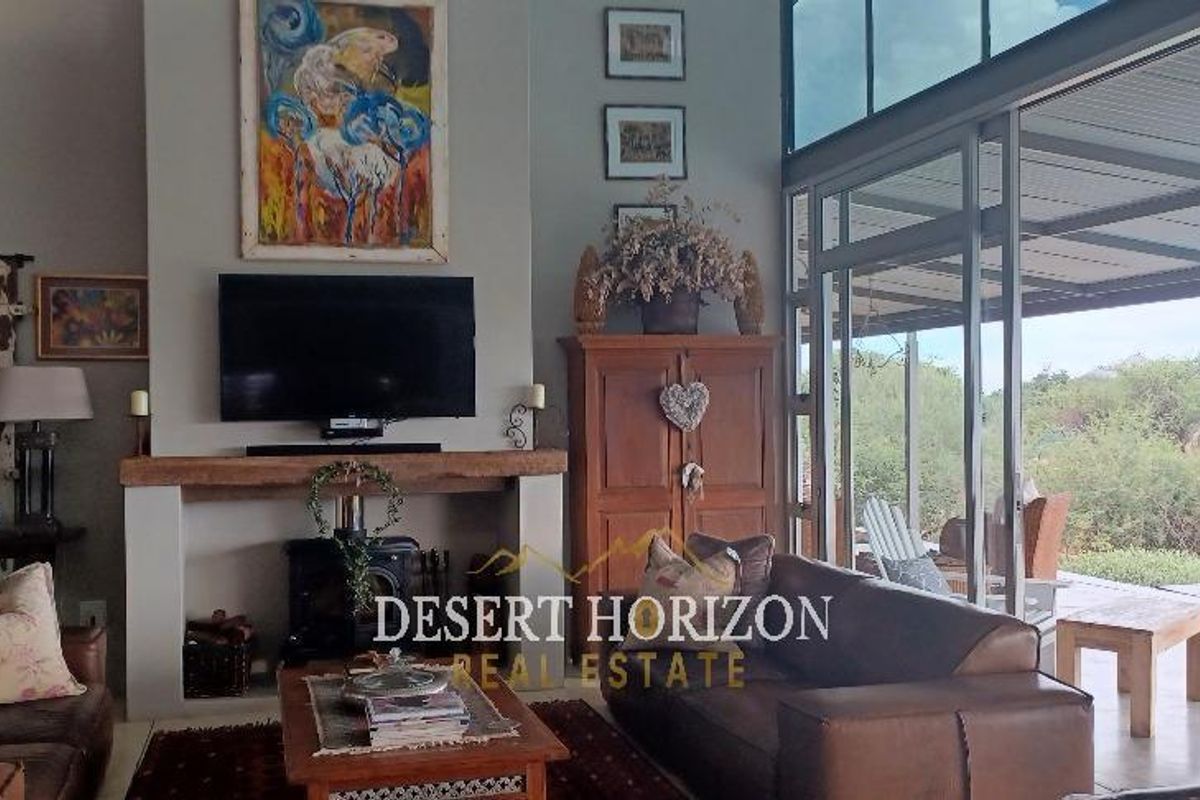 Spacious living room featuring a prominent fireplace, high ceilings, and large glass sliding doors that open onto a covered patio and pool area.