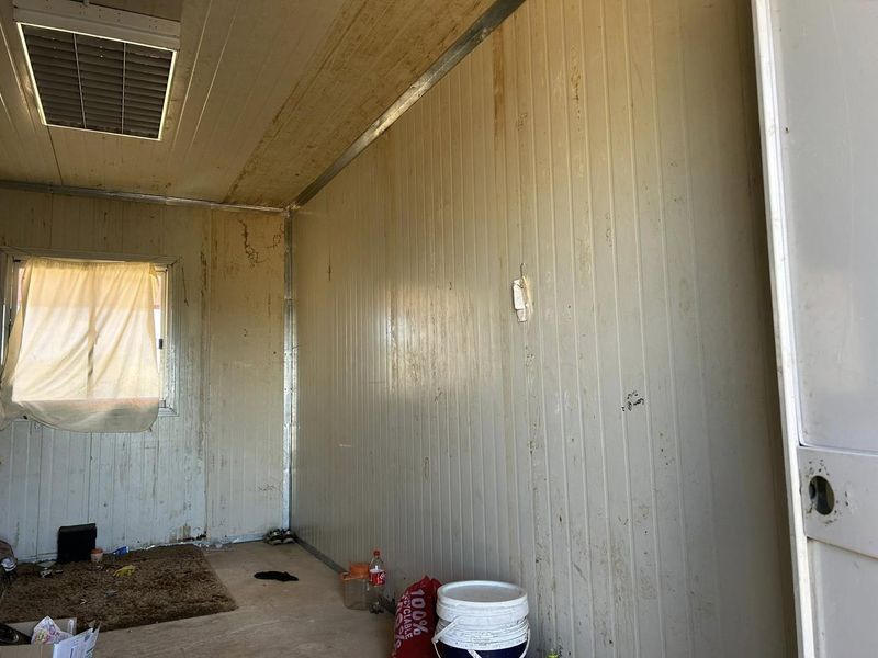 A basic utility space featuring insulated wall panels and a recessed ceiling light, currently in need of maintenance and cosmetic refurbishment.