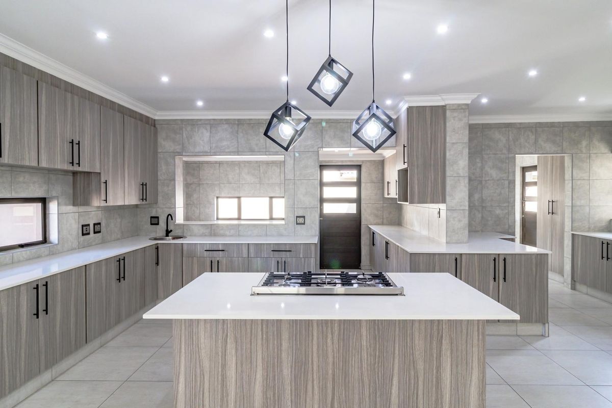 Modern kitchen featuring wood-grain cabinetry, stone countertops, a central island with a built-in gas hob, and recessed ceiling lighting.