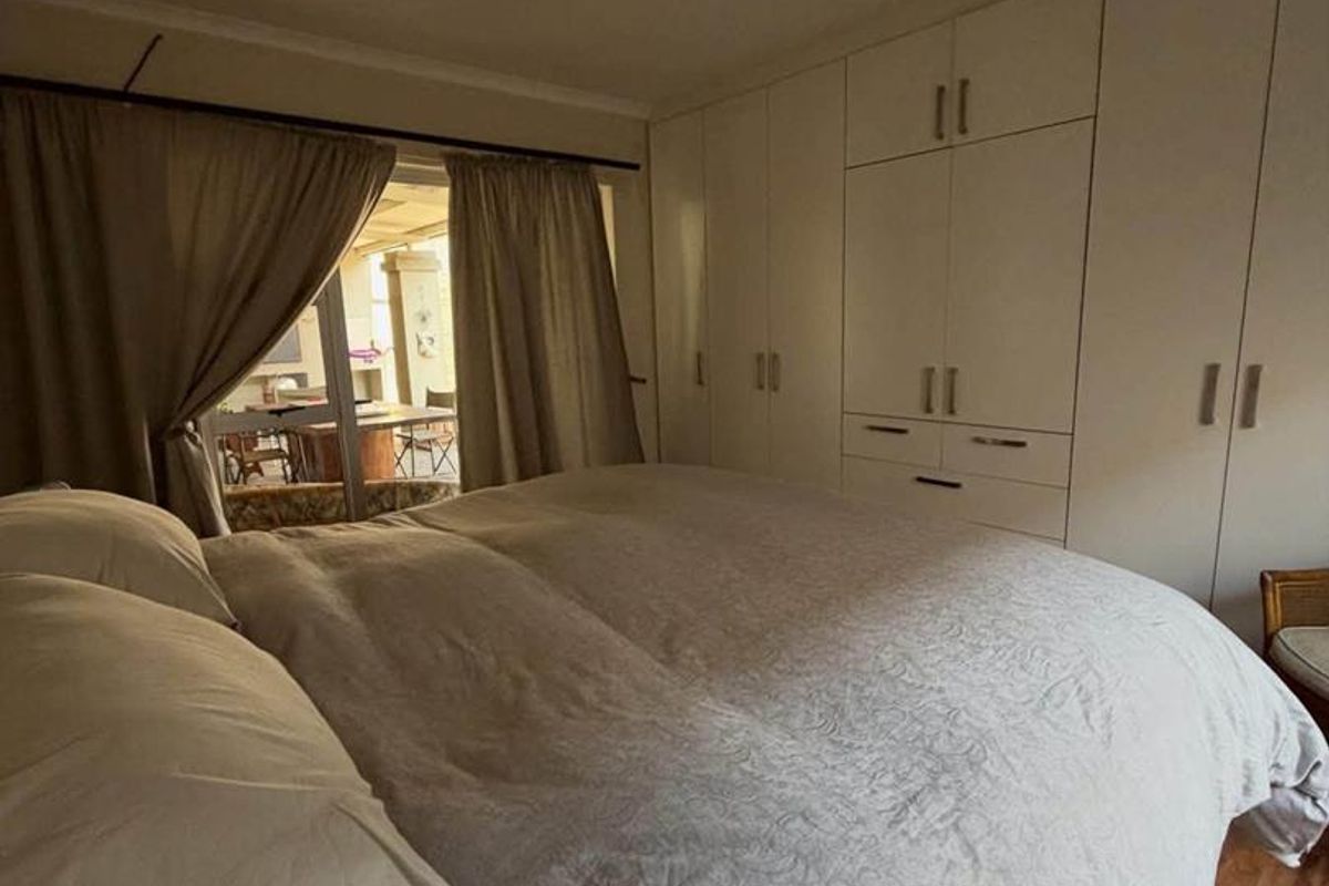 A bedroom featuring built-in cupboards, laminate flooring, and direct access to an outdoor patio area.