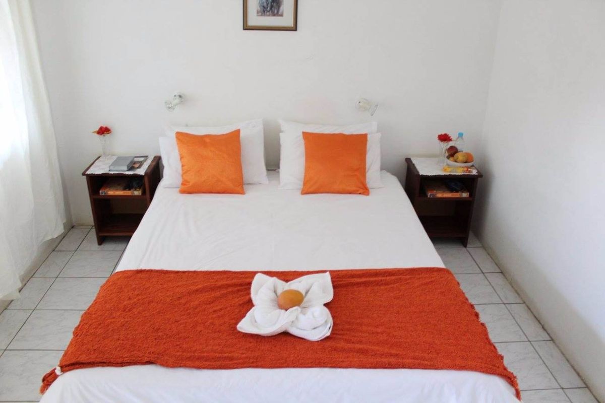 A simple guest bedroom featuring tiled flooring and wall-mounted reading lights.
