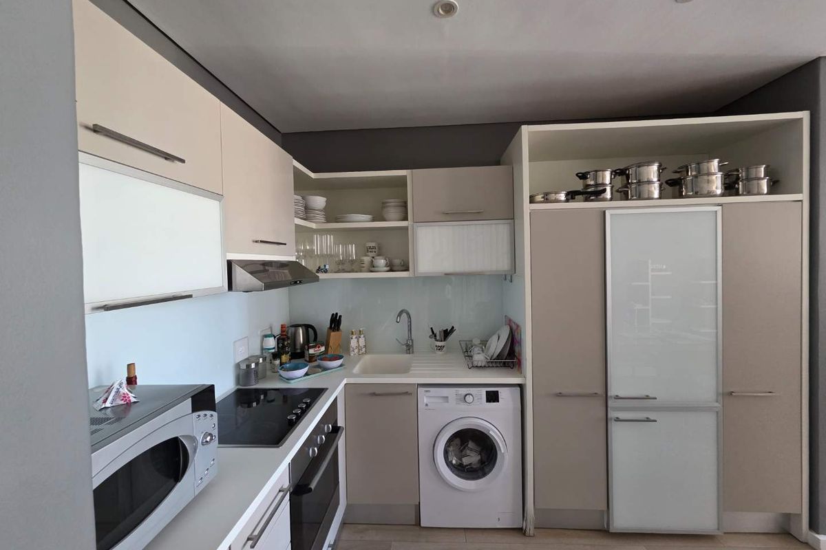 Modern compact kitchen featuring integrated appliances, sleek cabinetry, electric hob, built-in oven, and a convenient built-in washing machine.