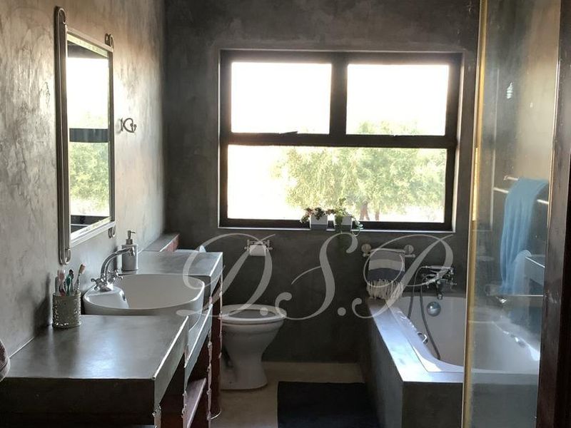 Modern industrial-style bathroom featuring a concrete vanity with vessel sink, built-in bathtub, and a glass-enclosed shower with polished concrete flooring.