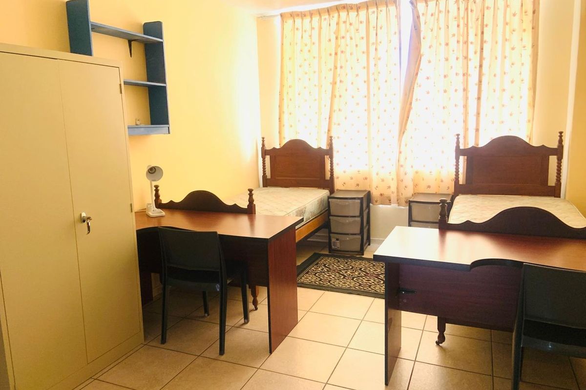 A functional bedroom featuring tiled flooring and built-in wall shelving, offering a practical layout for a shared living space.