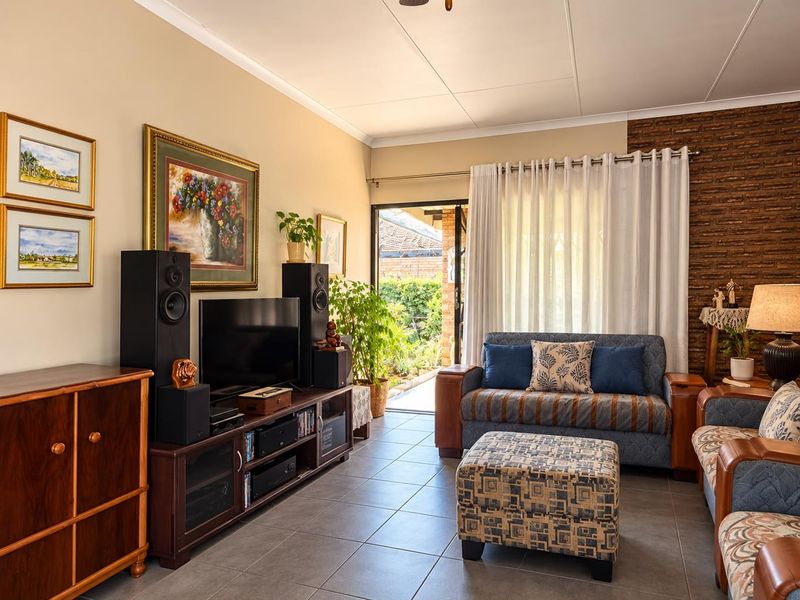 A comfortable living room featuring tiled flooring, an exposed brick accent wall, and a sliding glass door providing access to the outdoor area.