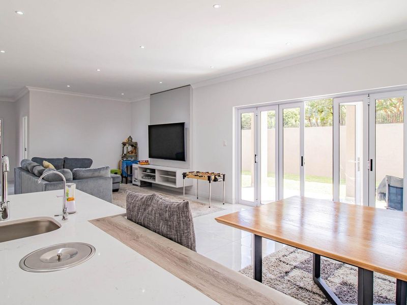 Spacious open-plan living area featuring a modern kitchen island, sleek tiled flooring, and large folding glass doors that open to the outdoor space.