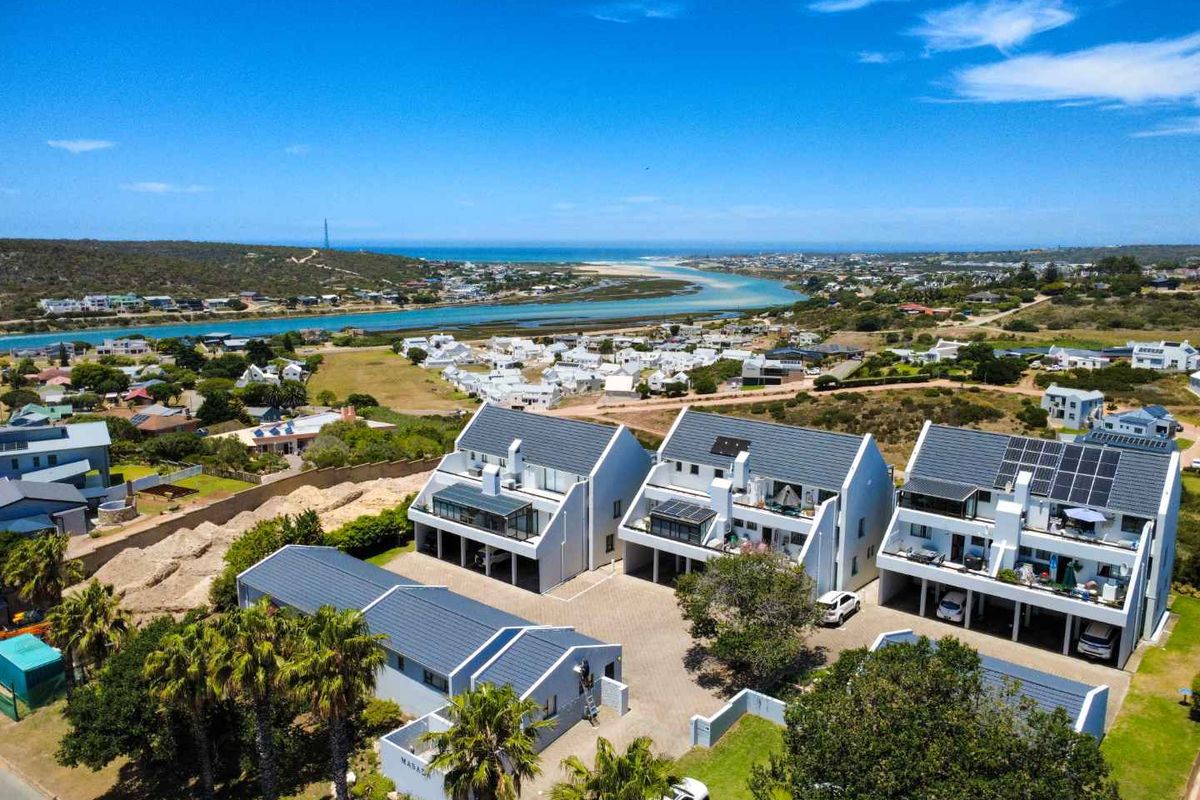 Aerial view of a modern apartment complex featuring pitched roofs, paved driveways, and proximity to the coastal estuary and surrounding landscape.