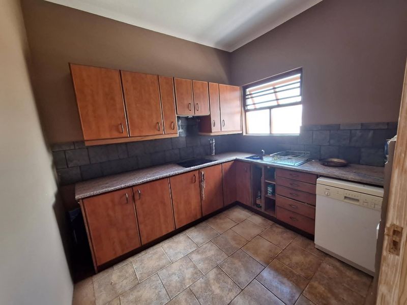 A dated kitchen featuring wood-look cabinetry, tiled backsplash, and ceramic flooring, currently requiring maintenance and cosmetic updates to improve functionality and aesthetic appeal.