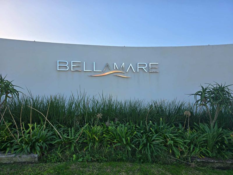 The entrance signage wall for the Bellamare estate, featuring landscaped garden beds at the base.