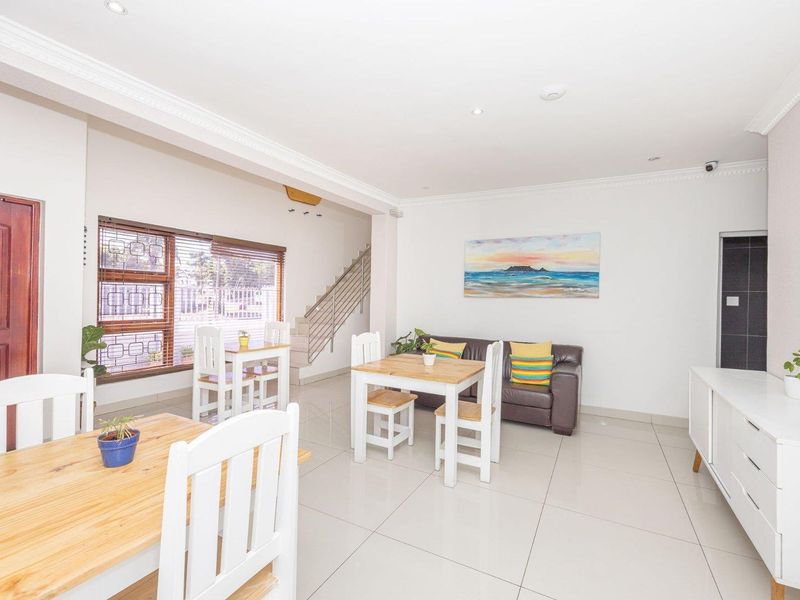Spacious open-plan living and dining area featuring neutral tiled flooring, recessed lighting, and a staircase with a modern metal balustrade.