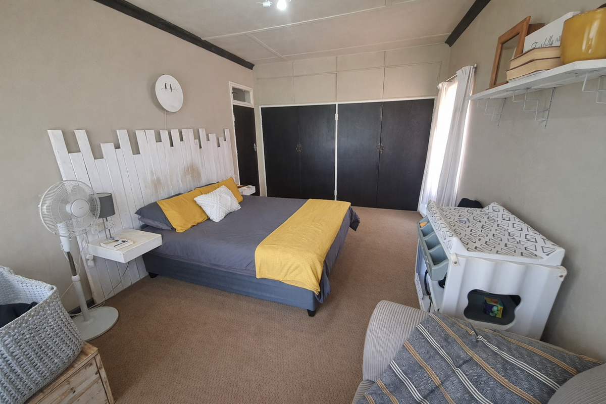 A spacious bedroom featuring built-in cupboards, neutral wall tones, and carpeted flooring, offering a functional layout with ample storage space.