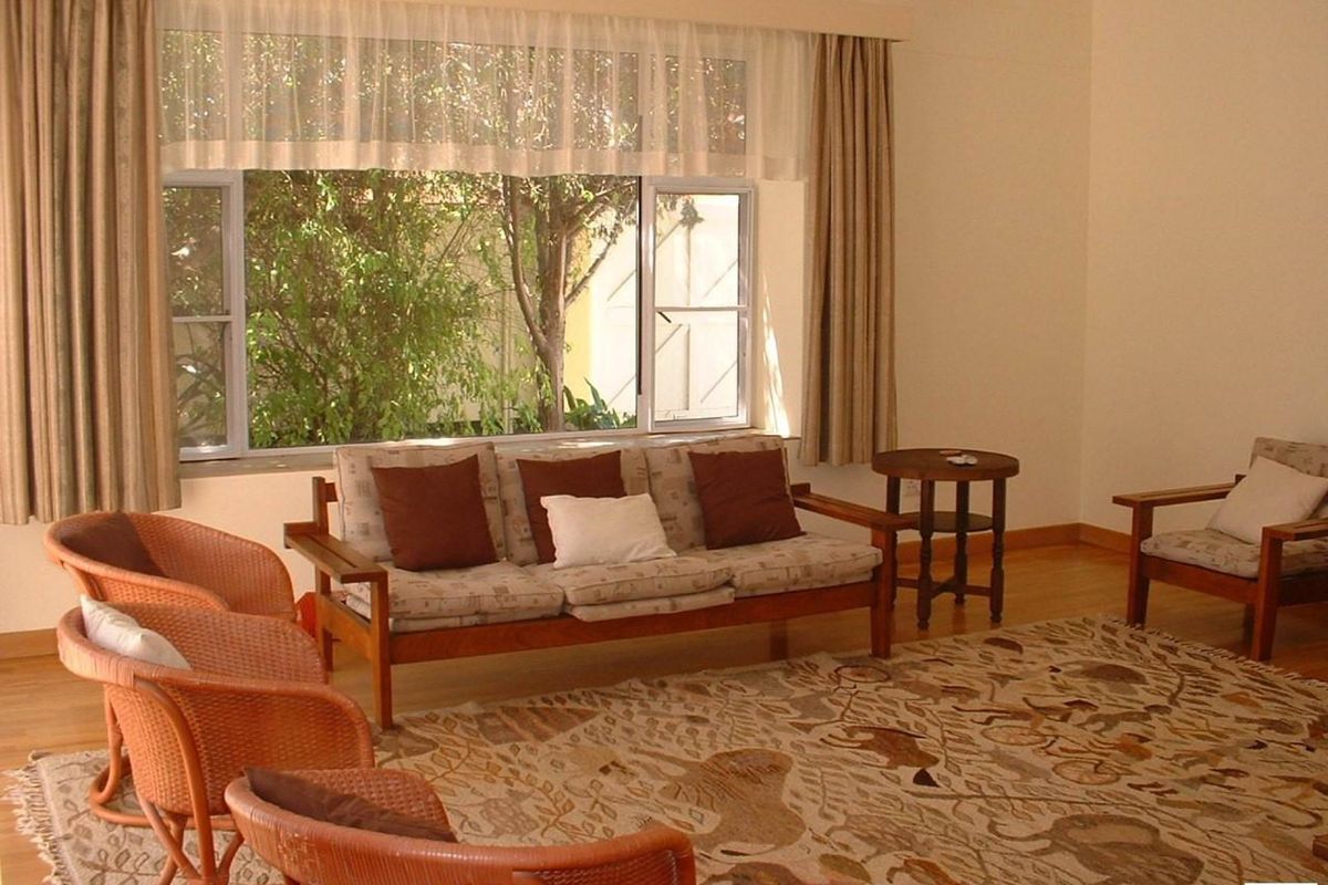 A bright and spacious living room featuring large windows that provide natural light and a pleasant view of the garden.