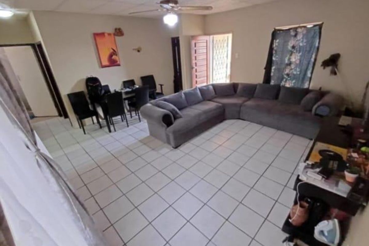 Spacious living area featuring tiled flooring, a ceiling fan, and direct access to an exterior entrance.