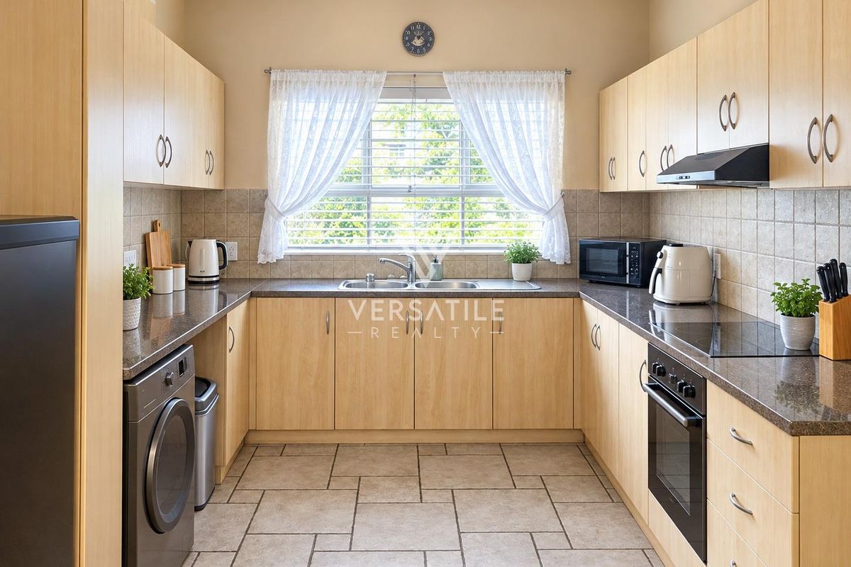 A functional U-shaped kitchen featuring light wood cabinetry, granite countertops, tiled backsplash, and integrated appliances including an oven and hob.