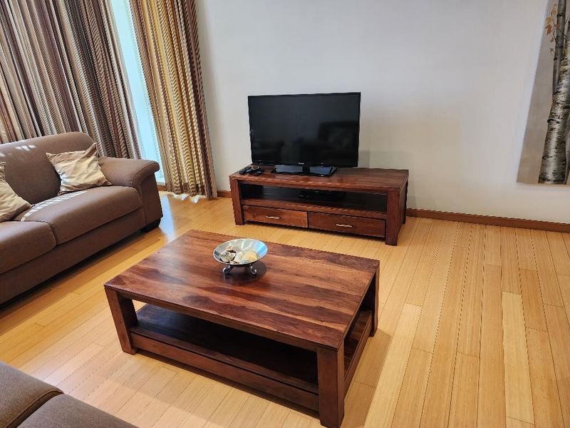 A well-maintained living room featuring warm-toned hardwood flooring and neutral wall finishes, providing a comfortable and inviting space.