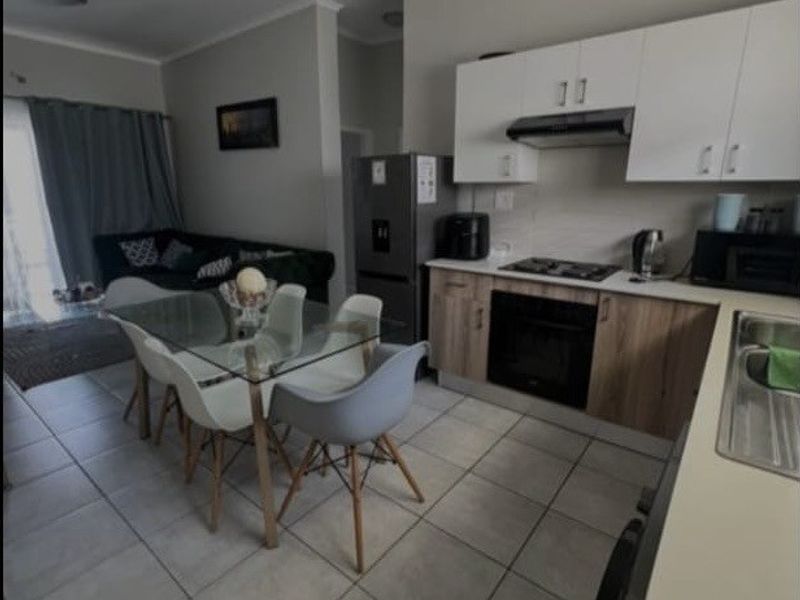 Open-plan living and kitchen area featuring modern cabinetry, built-in appliances, and tiled flooring, creating a functional and cohesive space.