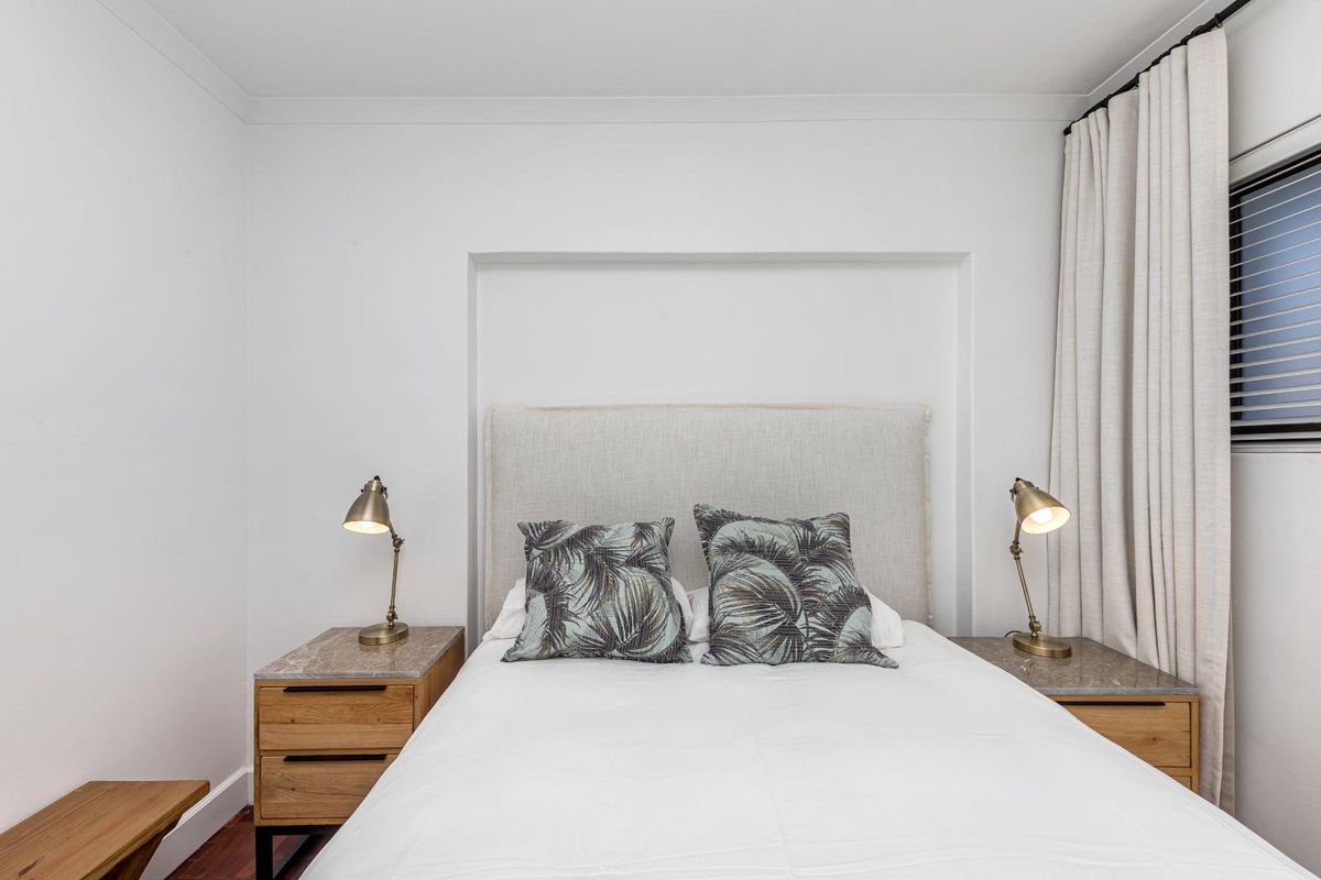 A well-maintained bedroom featuring a recessed wall niche, timber flooring, and neutral window treatments, providing a clean and comfortable living space.