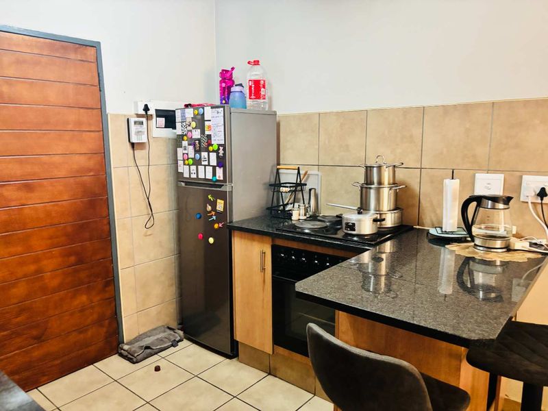 Compact kitchen featuring granite countertops, built-in oven, electric hob, and tiled backsplash, providing a functional workspace within the apartment.