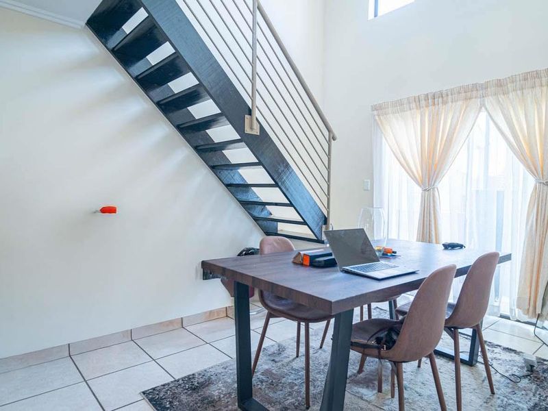 Open plan living area featuring a modern staircase with metal balustrade, tiled flooring, and access to a patio through sliding glass doors.