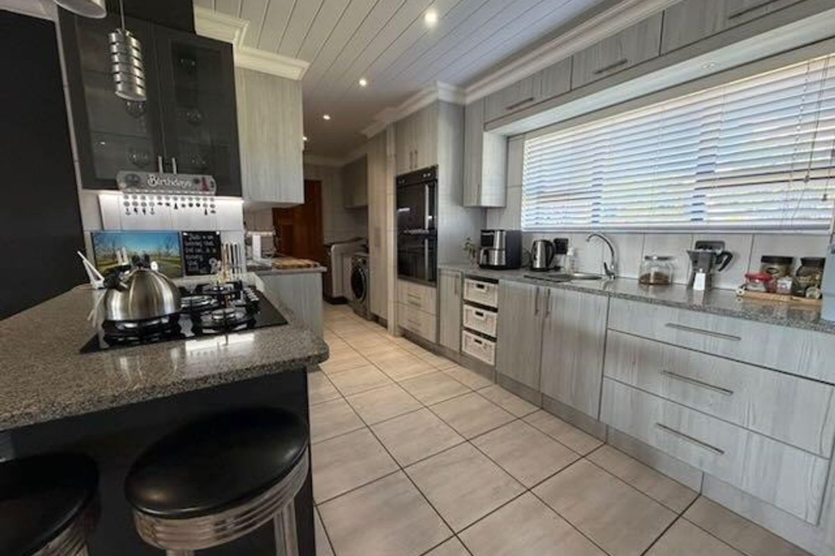 Modern kitchen featuring granite countertops, built-in oven, gas hob, and ample cabinetry, complemented by tiled flooring and a tongue and groove ceiling.