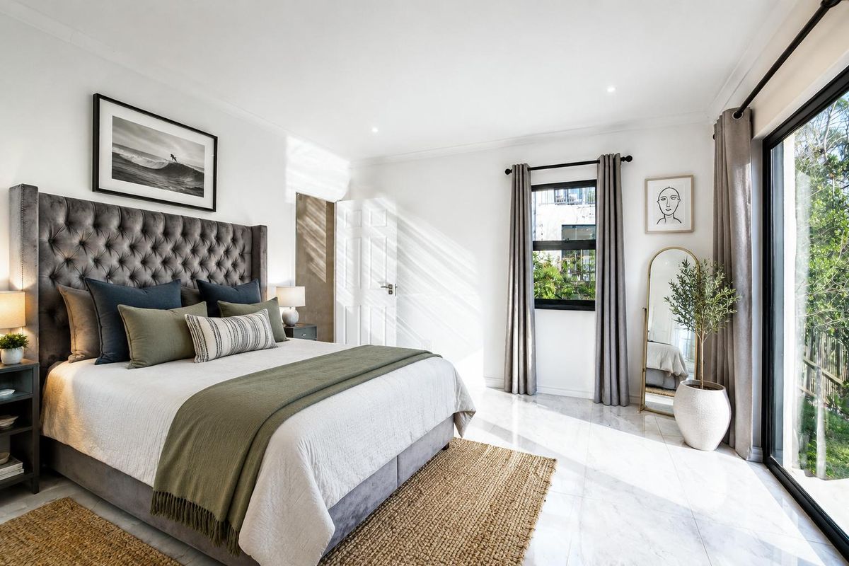 A bright and modern bedroom featuring polished tiled flooring, recessed lighting, and a large sliding glass door providing access to the outdoors.