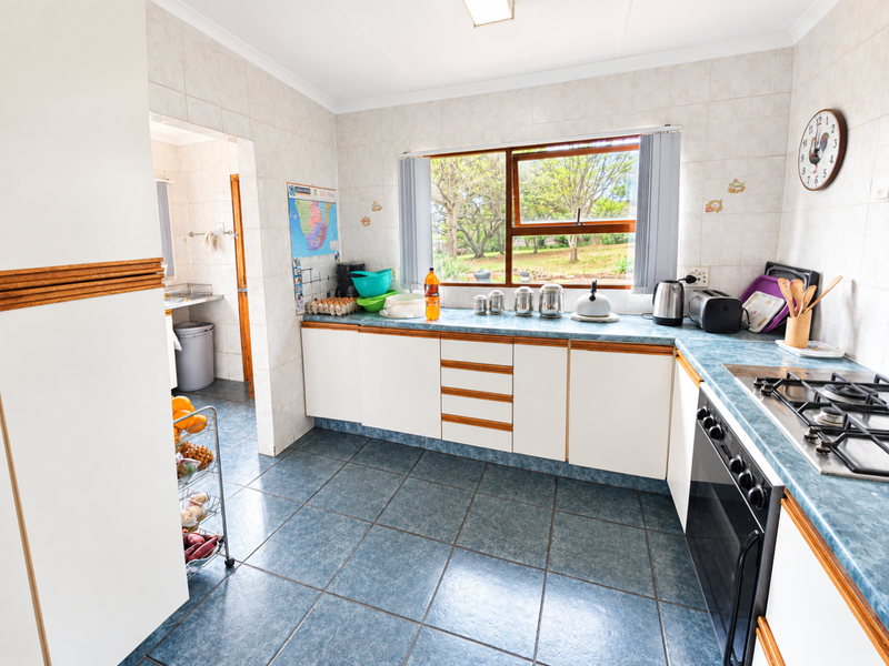 A functional kitchen featuring built-in cabinetry, a gas hob, an integrated oven, and tiled finishes, with an adjacent scullery area.