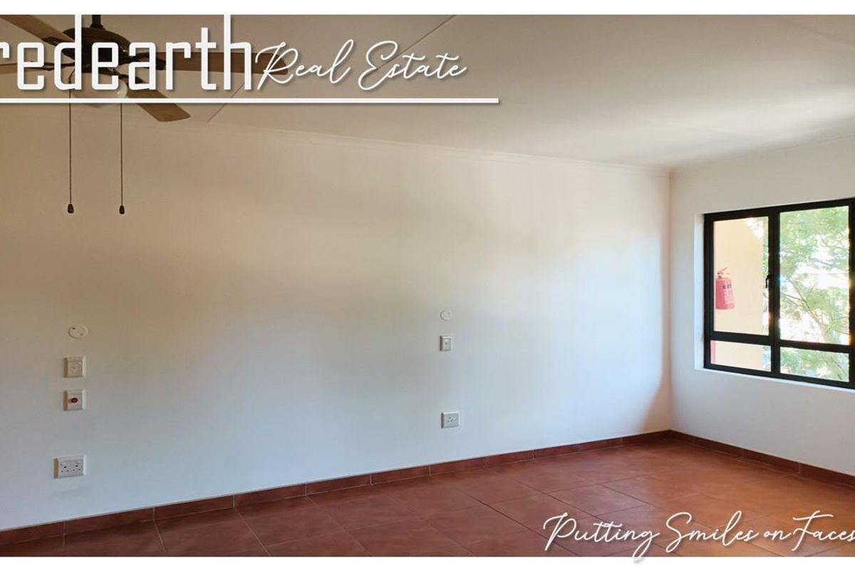 A vacant bedroom featuring tiled flooring, a ceiling fan, and large aluminium-framed windows providing natural light.