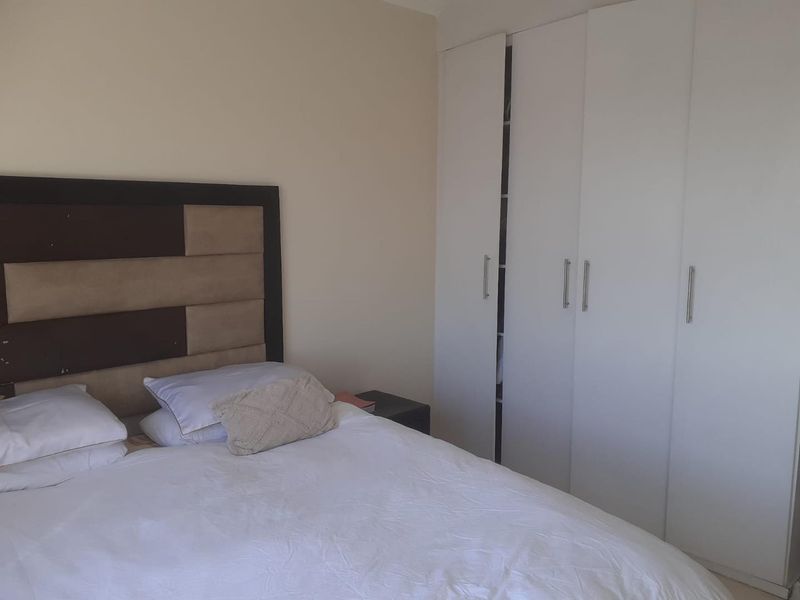 A bedroom featuring neutral walls and white built-in cupboards providing ample storage space.