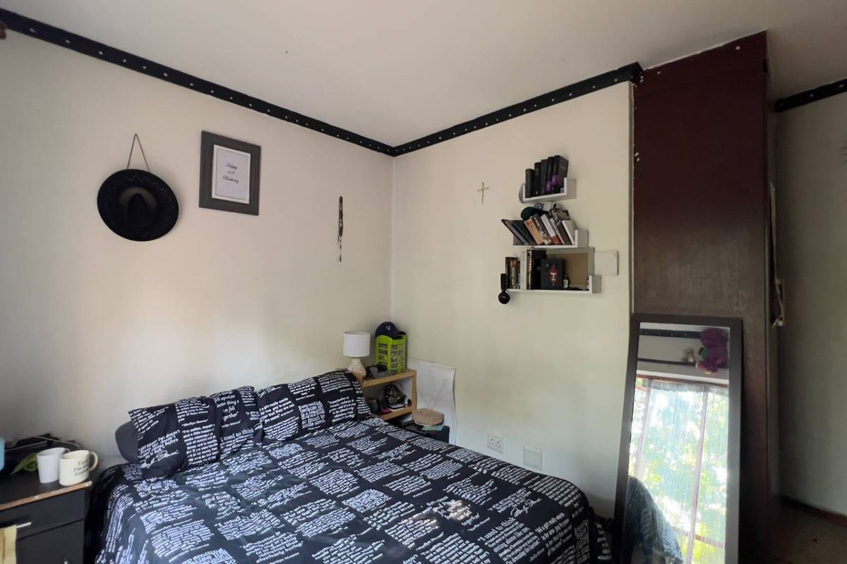 A bedroom featuring a built-in dark wood wardrobe, standard electrical outlets, and a decorative wall border.