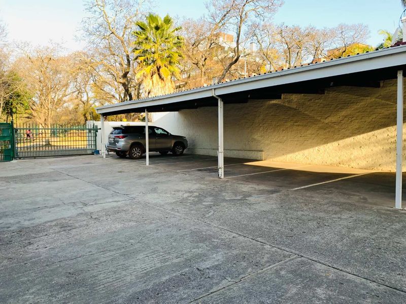 A covered carport area featuring a concrete driveway, metal support structure, and perimeter fencing, providing dedicated parking space.