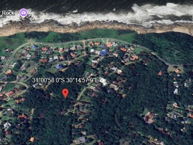 An aerial view of a residential area near the coastline, showing the surrounding landscape and proximity to the ocean.