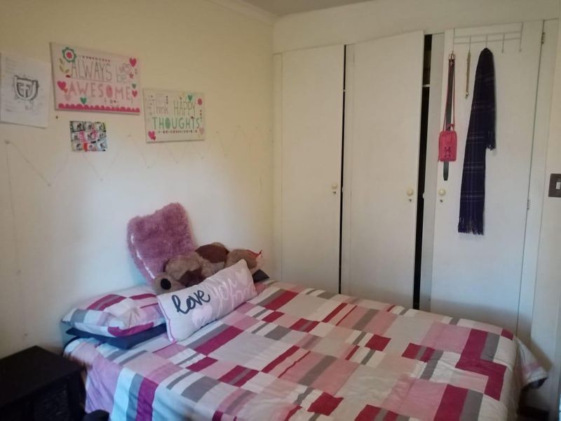 A functional bedroom featuring built-in wardrobe storage with white doors, providing practical space for clothing and personal items.