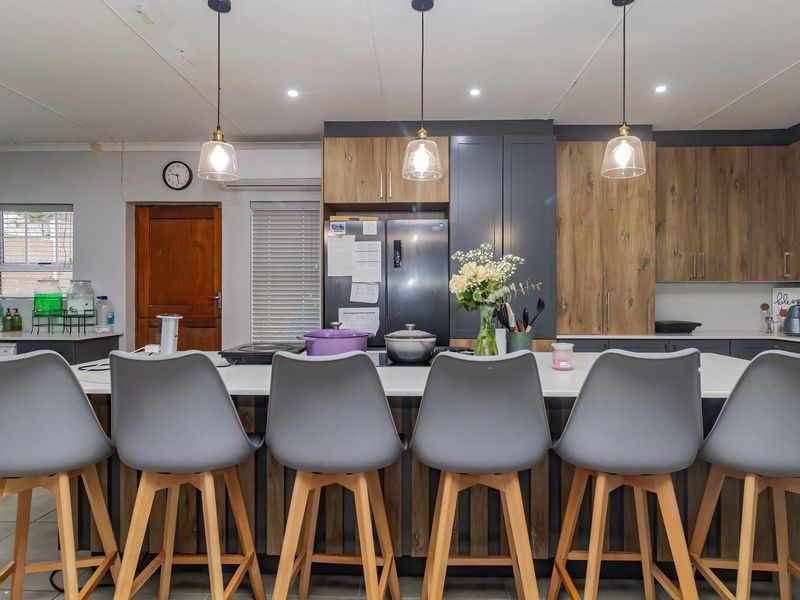 Modern kitchen featuring a large central island with breakfast bar seating, contemporary two-tone cabinetry, and stylish pendant lighting.