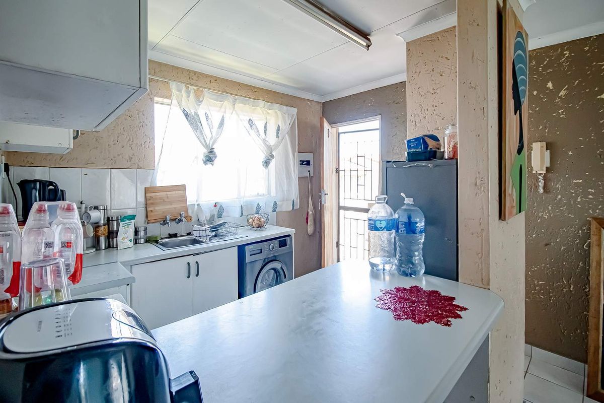 A functional kitchen featuring built-in cabinetry, a stainless steel sink, and a security gate, offering a practical layout with potential for modern updates.