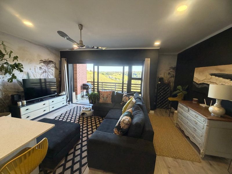 Spacious open-plan living area featuring recessed lighting, a ceiling fan, and large sliding glass doors that open onto a balcony with scenic views.