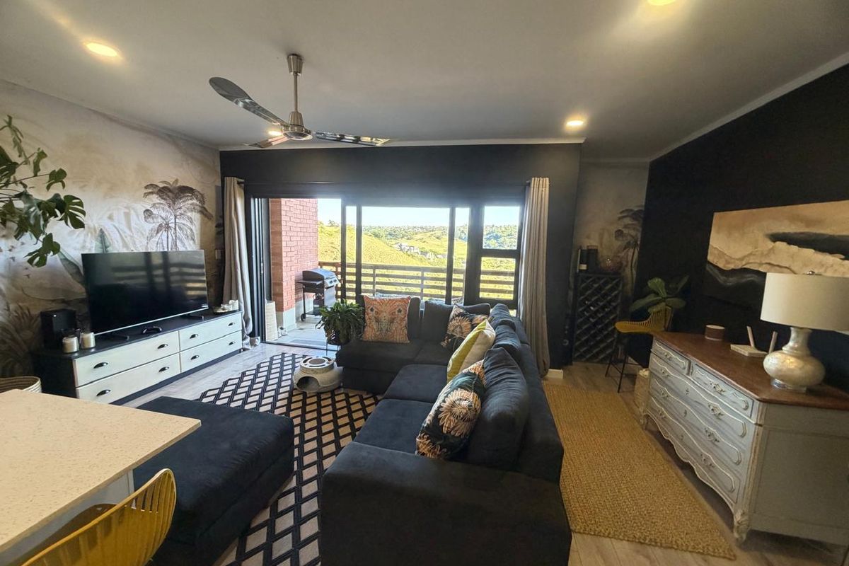 Spacious open-plan living area featuring recessed lighting, a ceiling fan, and large sliding glass doors that open onto a balcony with scenic views.