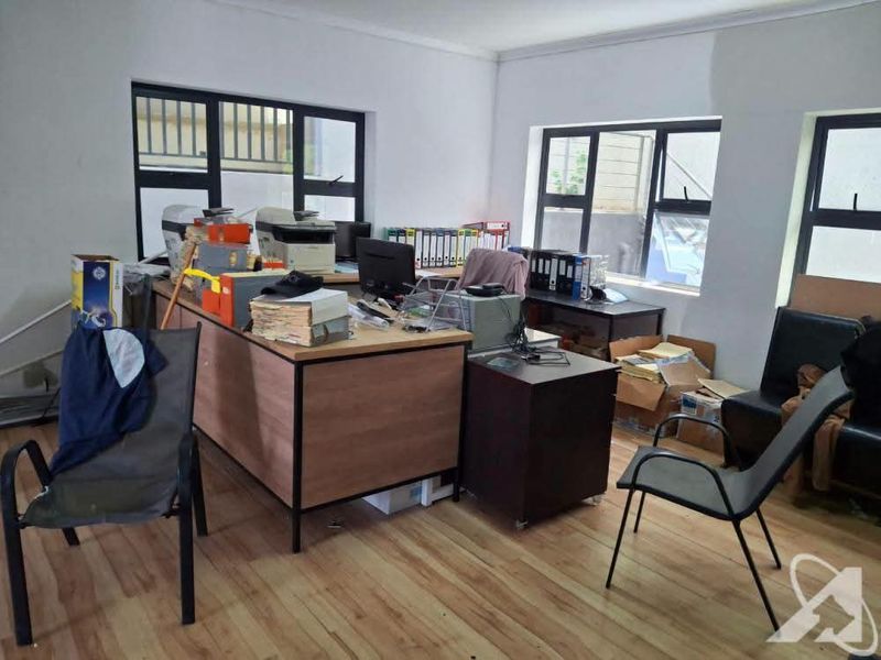 A functional office space featuring laminate flooring and large aluminium-framed windows, providing ample natural light for a productive work environment.