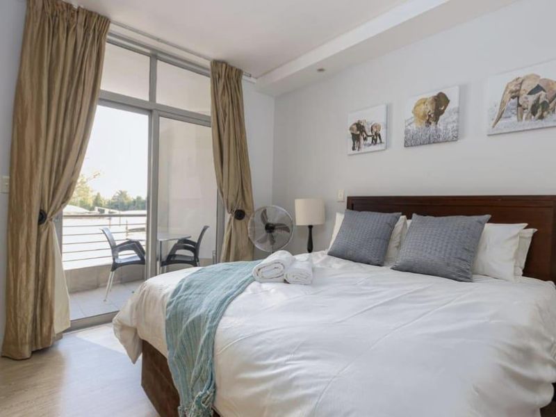 A well-lit bedroom featuring laminate flooring and a large sliding glass door providing direct access to a private balcony.