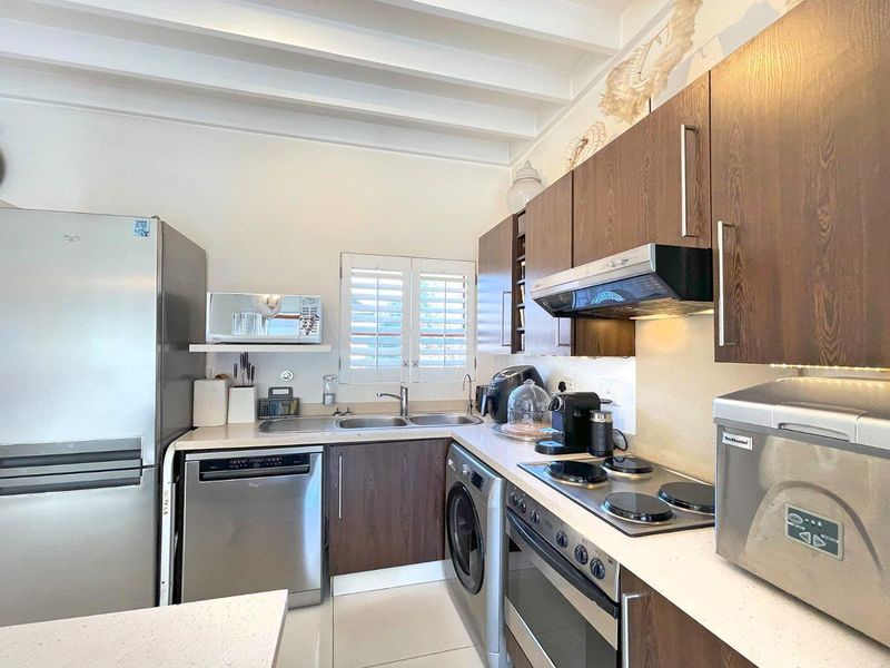A well-appointed kitchen featuring dark wood cabinetry, stone countertops, integrated appliances, and exposed ceiling beams, offering a functional and modern cooking space.