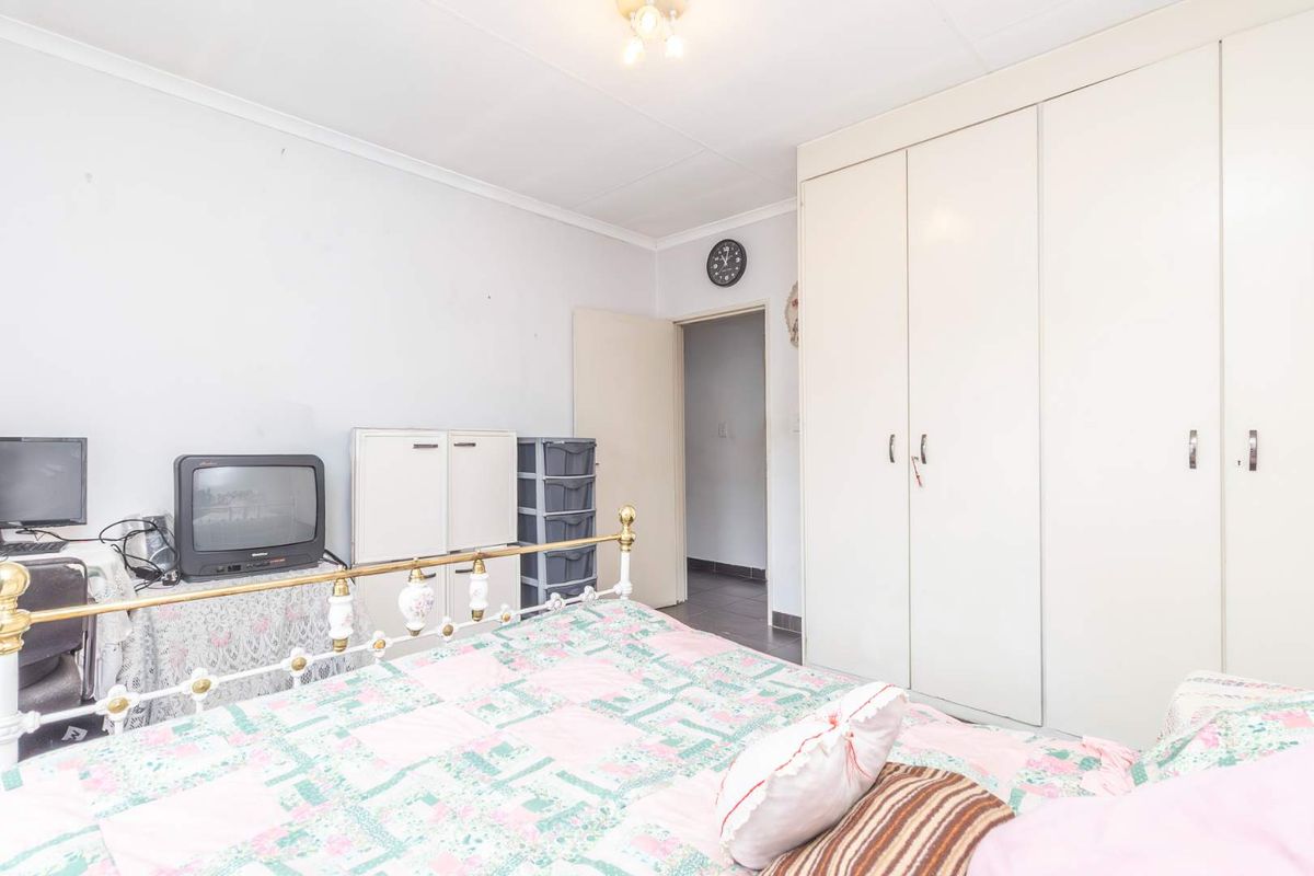 A bedroom featuring built-in cupboards and a doorway leading to an adjacent hallway.